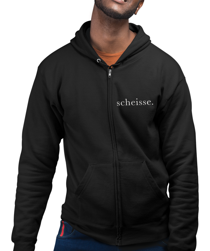 The design is the word scheisse. written in white lettering. The design is on the left side of the zipper on this black hoodie.